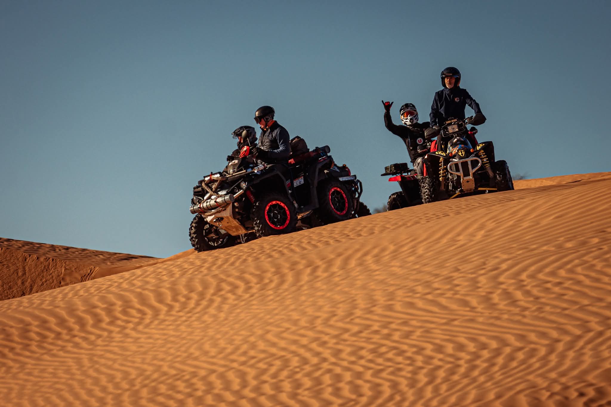 Quad riders crossing desert dunes